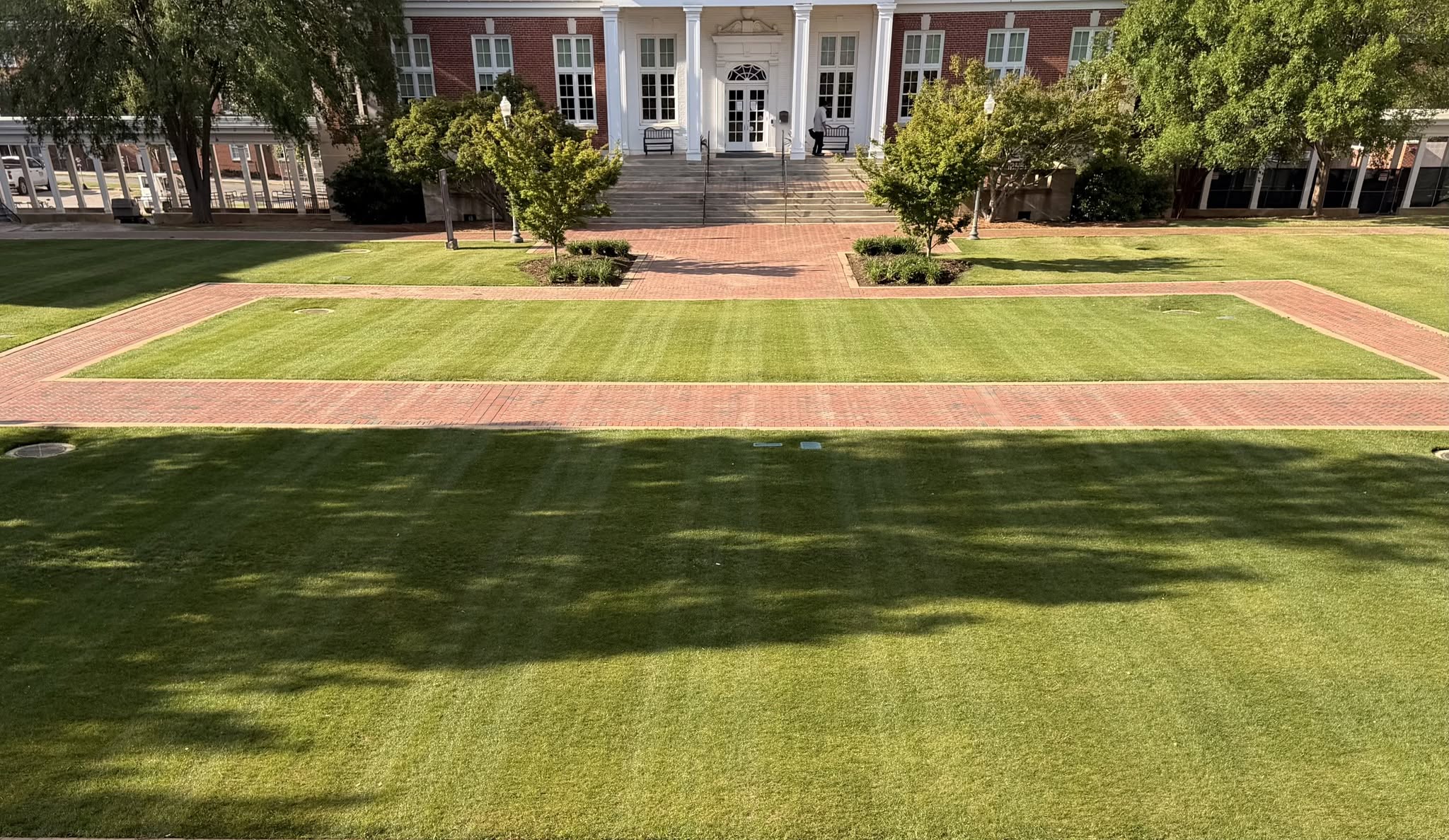 Brick walkways framing a precisely maintained formal lawn